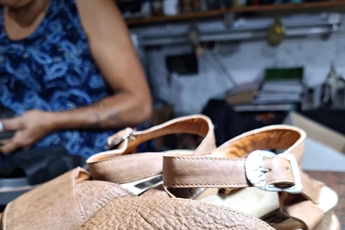 Marta armando una sandalia de cuero en la mesa del taller